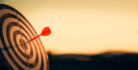 bullseye target or dart board has red dart arrow throw hitting the center of a shooting for...