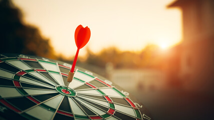 bullseye target or dart board has red dart arrow throw hitting the center of a shooting for...