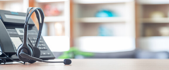 Close up soft focus on headset with telephone devices at office desk for customer service support.VOIP headset for customer service support (call center) concept.