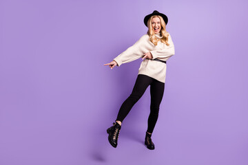 Full body photo of excited happy nice woman point finger empty space dance isolated on violet color background
