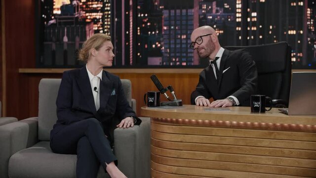 FIXED Late-night talk show host showing a green board with tracking points to female celebrity polititian guest in a studio. TV broadcast style show. Shot with RED cinema camera