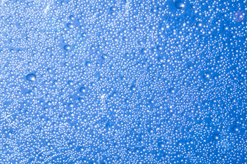Rain drops on clear glass with sparkling sunlight On the blue sky background