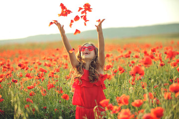 Beautiful child girl in a field of poppies, outdoor portrait. Child in a field with flowers. High...