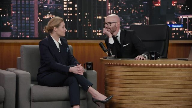 ZOOM IN Late-night talk show host having a conversation with celebrity female guest in a studio. TV broadcast style show. Shot with RED cinema camera