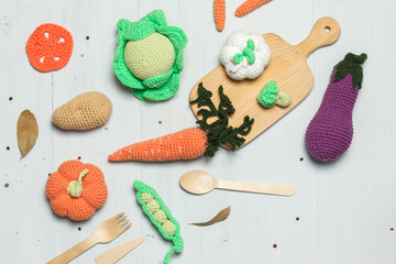Naklejka na ściany i meble Amigurumi, knitted toy vegetables and wooden cutlery. Layout on a light background with space