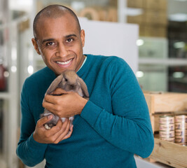 Portrait of smiling man holding little rabbit in pet shop