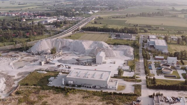 Drone shot of white sand mountain by the construction site. Building road in the city suburbs.
