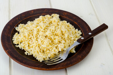 Boiled bulgur groats, vegetarian porridgeon plate. Studio Photo