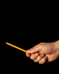 Close up of male hand holding pencil on black isolated background