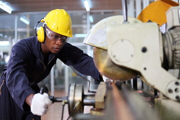 African American mechanic engineer worker wearing safety equipment is cutting copper tube using...