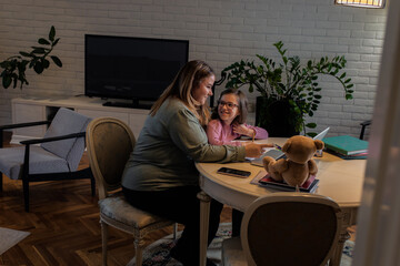 Fototapeta premium Mother and daughter follow online classes using laptop at home.