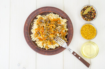 Boiled bulgur groats with stewed vegetables and mushrooms, vegetarian food.