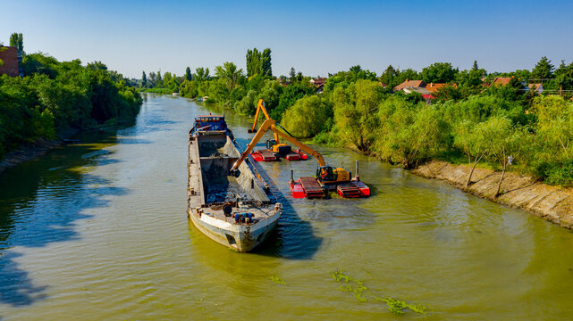 Aerial view of river, canal is being dredged by excavators