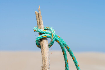 Green rope with knot in a rusty cane against blue sky