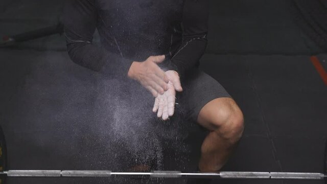 Cropped fitness sporty man rubbing hands with chalk magnesium powder, young male preparing for workout. Sport and fitness, bodybuilding concept