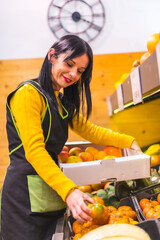 Portrait of brunette fruit girl working ordering fruits in a greengrocer establishment, vertical photo