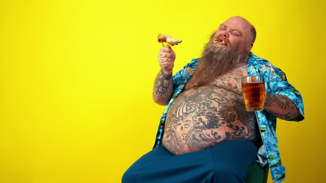 Funny man watching television. Big fat hipster with tattoo on yellow colored background