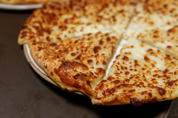 Khachapuri freshly prepared on a plastic tray close-up. A dish prepared in a restaurant.