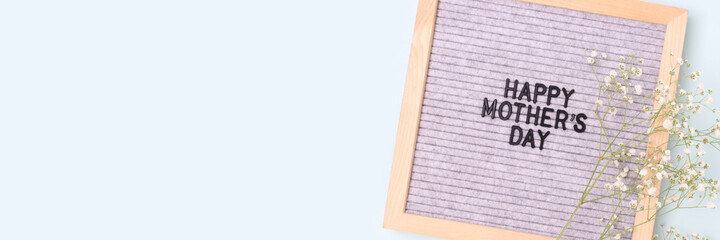 Happy Mothers day. Banner with letter board and gypsophila flower on a blue pastel background. Festive concept with copyspace.