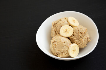 Homemade Peanut Butter Banana Ice Cream in a Bowl on a black surface, side view. Copy space.