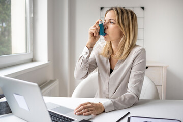 Business woman with asthma inhaler in office - obrazy, fototapety, plakaty