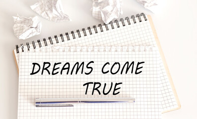 Text on notepad Dreams Come True on the white background. Business Concept