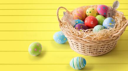 Fototapeta na wymiar easter, holidays, tradition and object concept - close up of colored eggs in basket over yellow wooden boards background