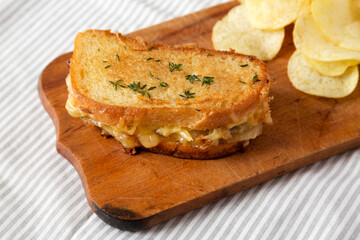 Homemade French Onion Melt Cheese Sandwich with Chips on a rustic wooden board on cloth, low angle view. Close-up.