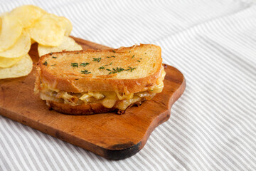 Homemade French Onion Melt Cheese Sandwich with Chips on a rustic wooden board on cloth, low angle view. Copy space.