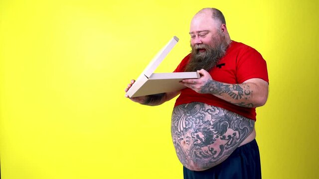 Cinematic footage of a funny man with hispter beard acting on a colored background. Happy man sniffing and tasting the italian pizza at home