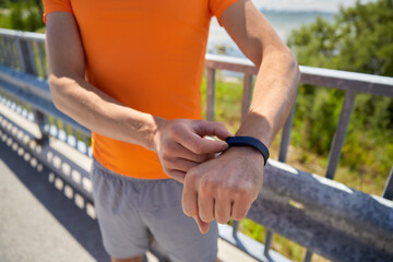 fitness, sport and healthy lifestyle concept - close up of young man with fitness tracker at seaside