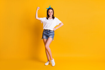 Fototapeta na wymiar Photo portrait of cheerful pin-up girl demonstrating strong biceps triceps smiling isolated vibrant yellow color background