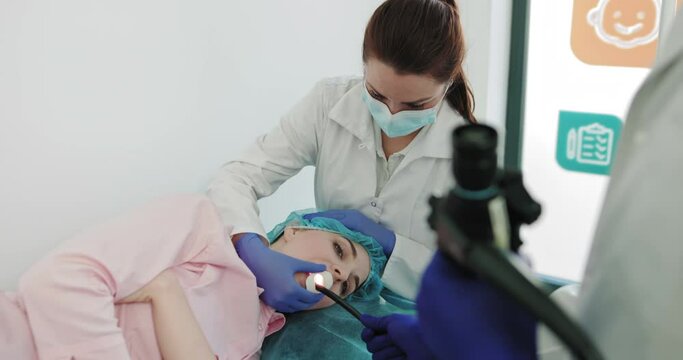 Two Surgeons Perform Endoscopic Surgery Using Modern Equipment. Medical Team Examining Colon Of Patient Who Lying On Bed, Gastroenterologist With Joystick Control Micro Camera For Colonoscopy