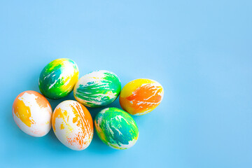 Top view of multicolored Easter eggs on a blue background. Happy Easter card. Dyed Easter eggs. Copy space for your text. Flat lay style. Top view. 