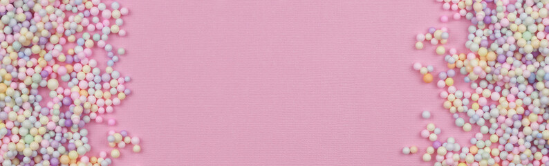 Small colorful pastel balls in a borders on pink paper