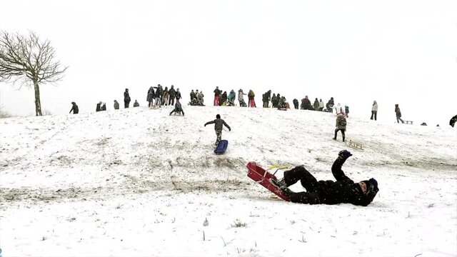 Time lapse. In winter snowy day people are sledding from the ice slide.