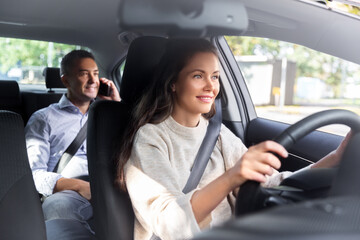 Fototapeta premium transportation, vehicle and people concept - happy smiling female driver driving car with male passenger calling on phone