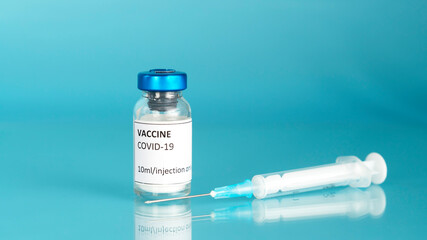 Coronavirus vaccine vial. Covid vaccination with vaccine glass bottle and syringe. Blue background.