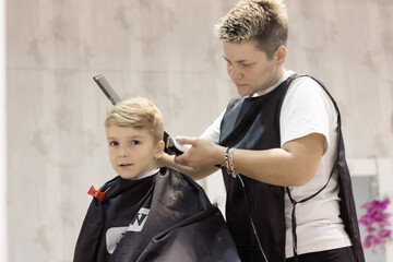 Cute kid having a haircut at barber shop.