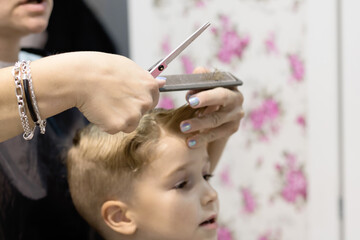 Close-up of hairdresser cutting boy's hair at the salon.