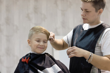 Happy boy having a haircut at hair salon.