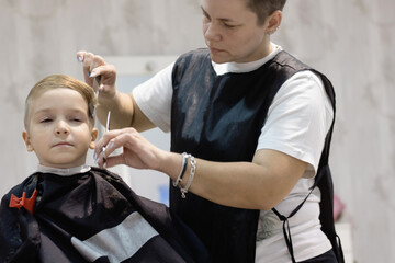 Small boy getting his hair styled by hairdresser.