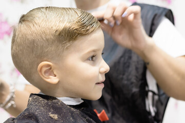 Close-up of boy getting a hairstyle at hair salon.