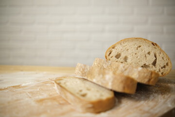 Bread sliced and freshly baked on a wooden table. Flour, bakery. The cooking process is captured in 4k resolution. White brick background. Selective Focus