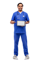 medicine, healthcare and technology concept - happy smiling indian doctor or male nurse in blue uniform with stethoscope showing tablet pc computer over white background