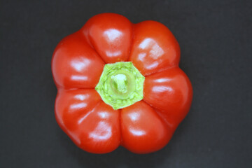 The fruit of a red sweet pepper on a black background.
