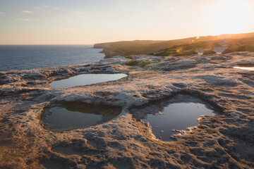 Rocky, cliff seafront coastline and rock pools in the Royal National Park on as the sun sets in the eastern suburbs of Sydney, NSW, Australia.