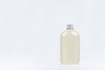 Transparent plastic low thick bottle with pale fresh drink or cosmetic essential oil with silver cap mockup on white background, template, copy space.
