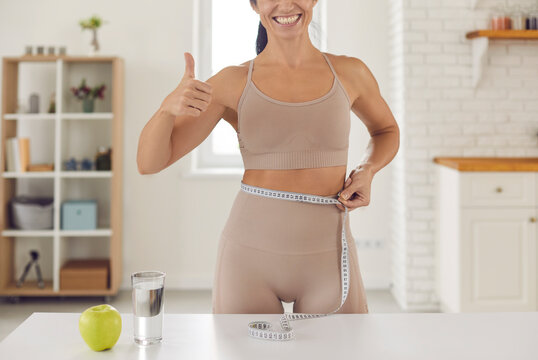 Body care. Cropped image of a fitness woman wrapped in a measuring tape and lifting her thumb up showing that the result is great. Woman showed a good result from a balanced diet and exercise.