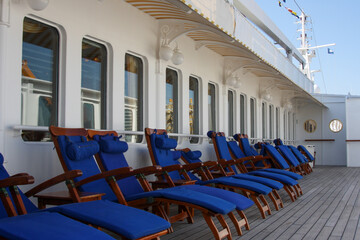 Elegant wooden teak deck chairs and sun loungers with blue covers on luxury cruiseship or cruise...